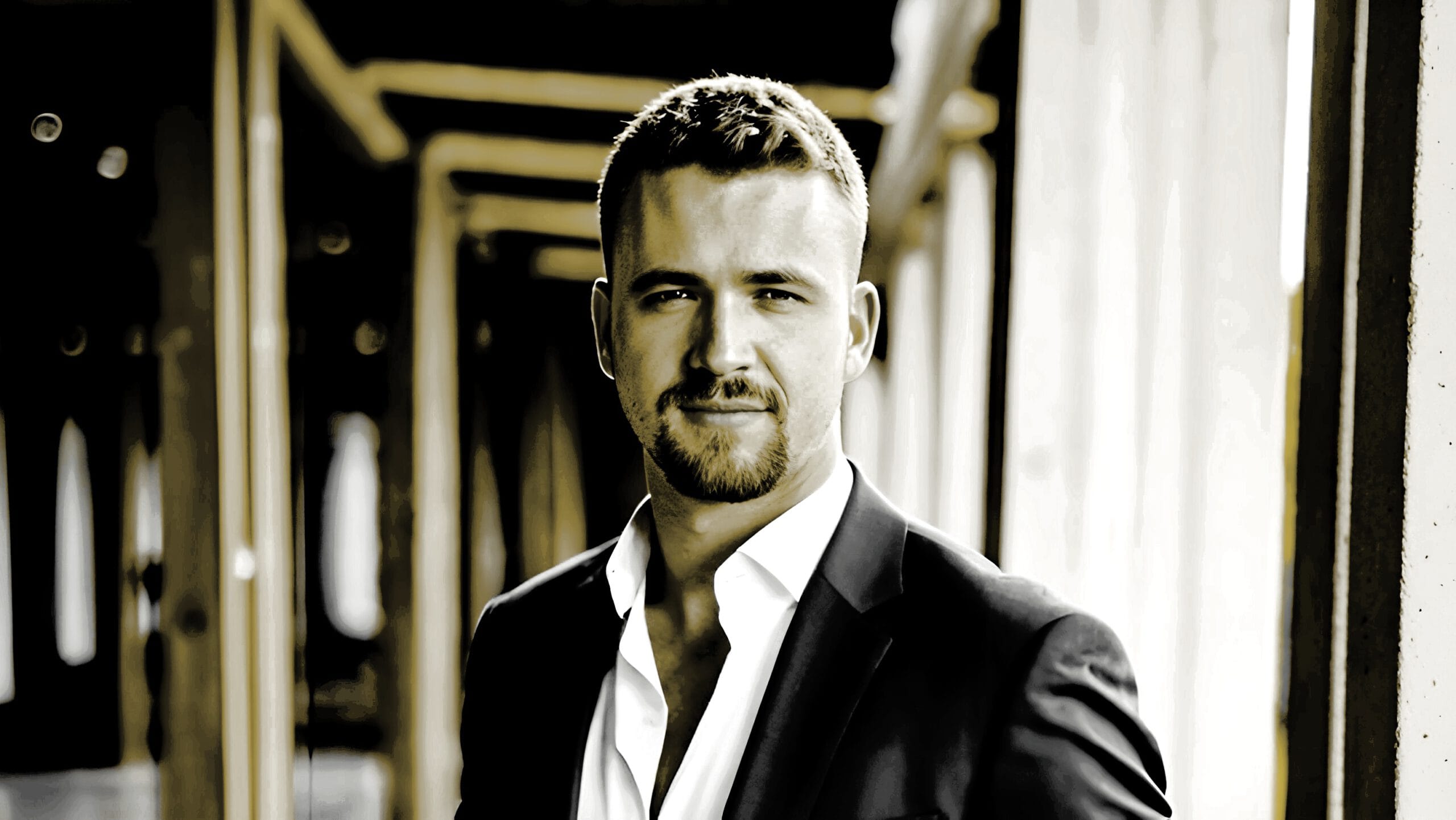 Benedikt Gruber im Business-Anzug lächelt professionell in die Kamera vor neutralem Hintergrund