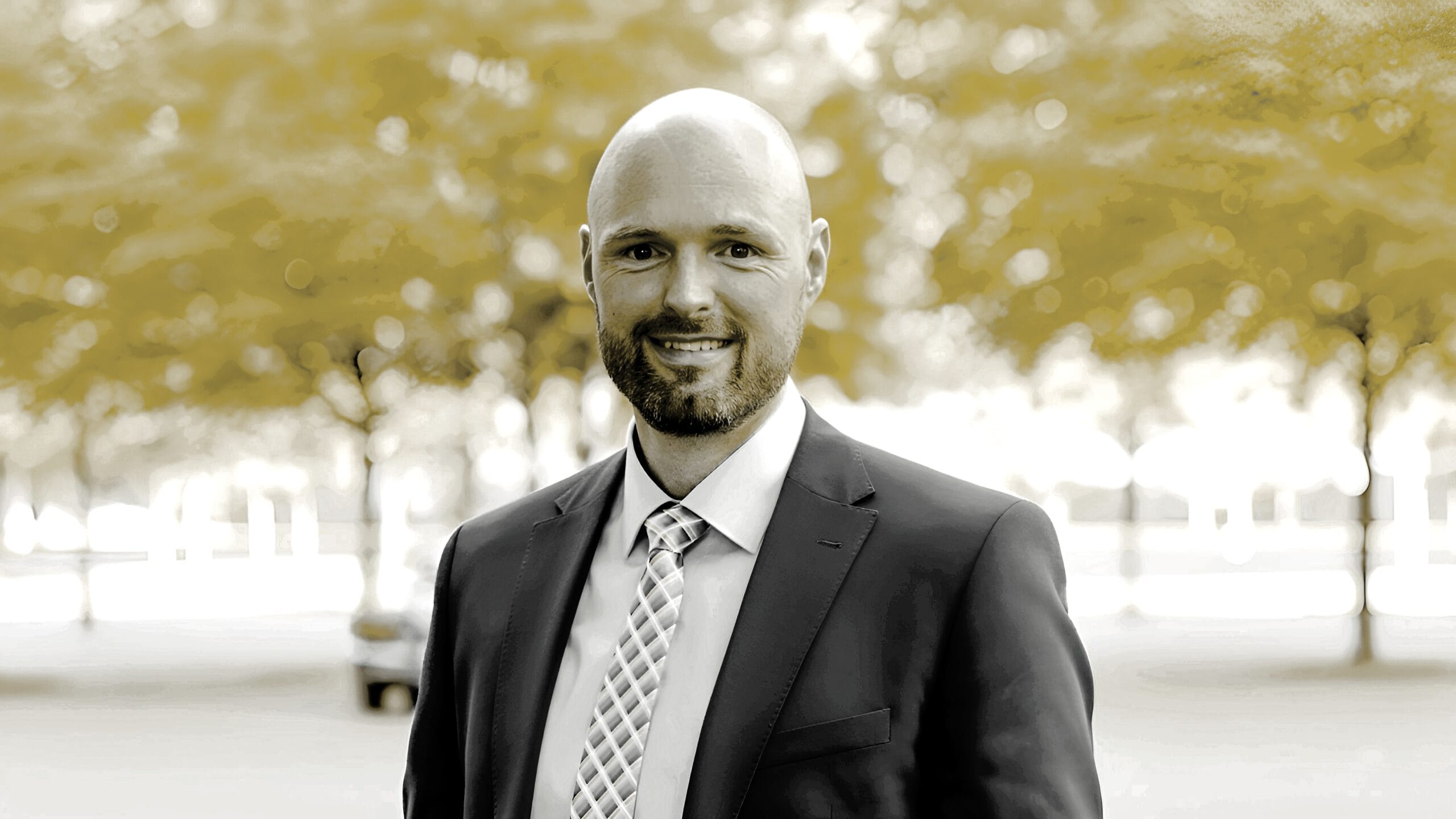 Alexander Hofmann, Immobilienmakler in Hannover, steht lächelnd vor einem Haus und hält einen Schlüssel in der Hand