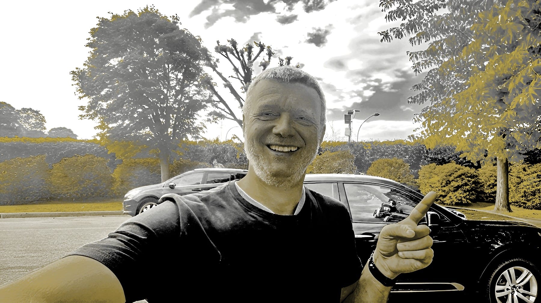 Andreas Wendler Messebau Chef mit Daumen hoch vor Auto - erfolgreicher Unternehmer zeigt Business-Power