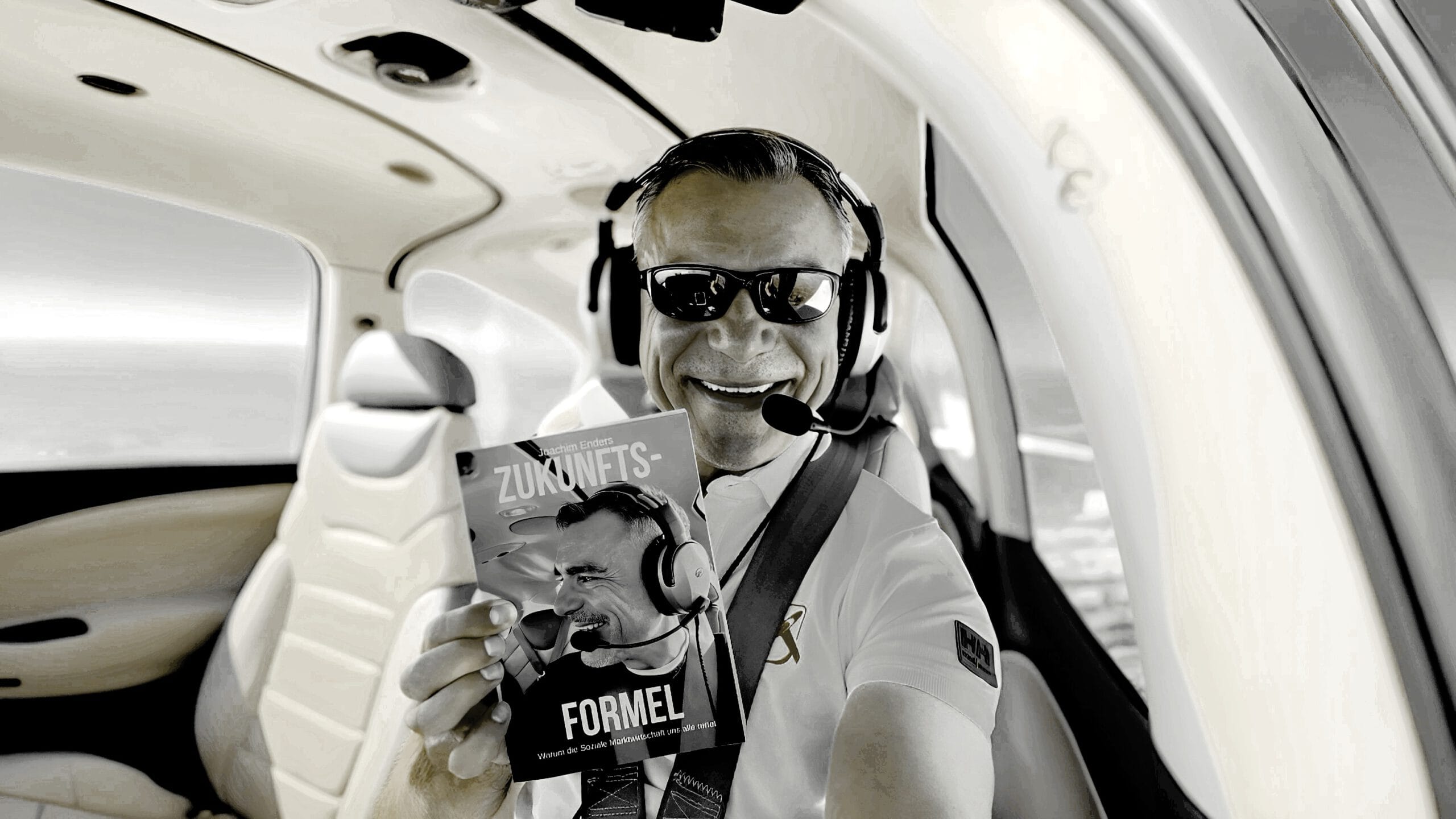 Erfolgreich mit Joachim Enders Zukunftsformel: Pilot mit Headset liest Wirtschaftsbuch im Cockpit