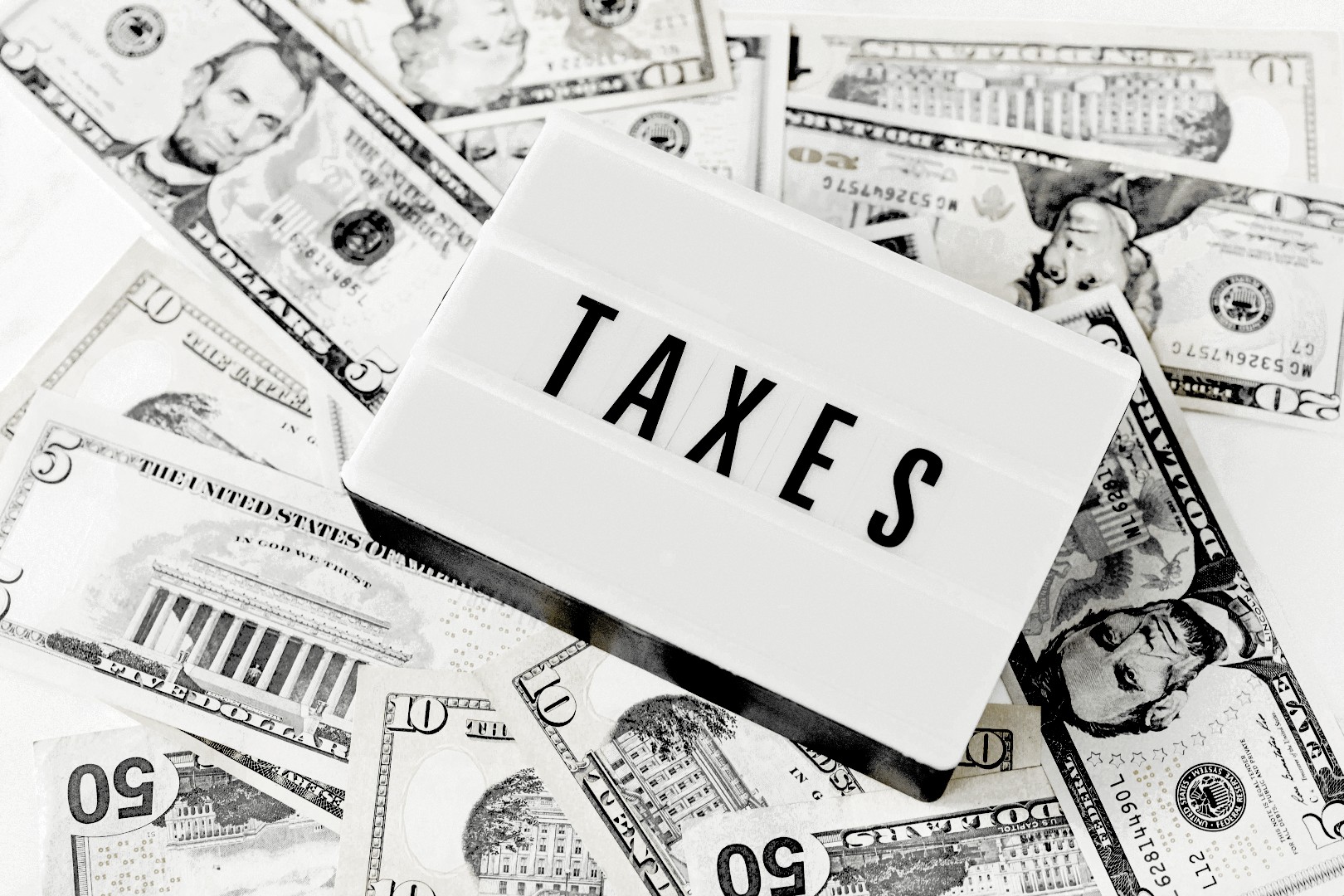 Geschlecht ändern Steuern sparen 2026: Dollarscheine und TAXES-Schild symbolisieren kreative Steuergestaltung