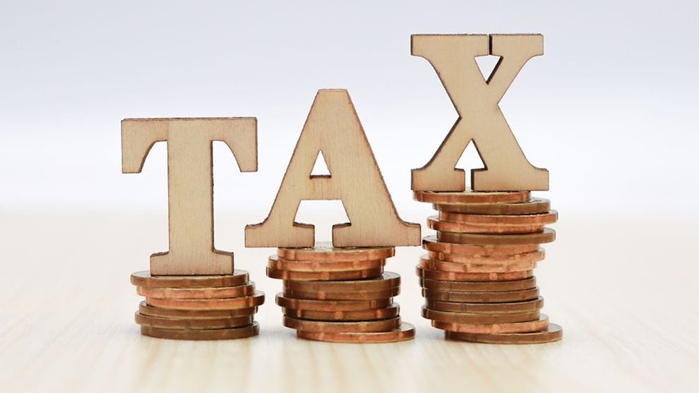 Steuern sparen englische Gesellschaft: TAX-Buchstaben auf steigenden Münzstapeln symbolisieren Steueroptimierung